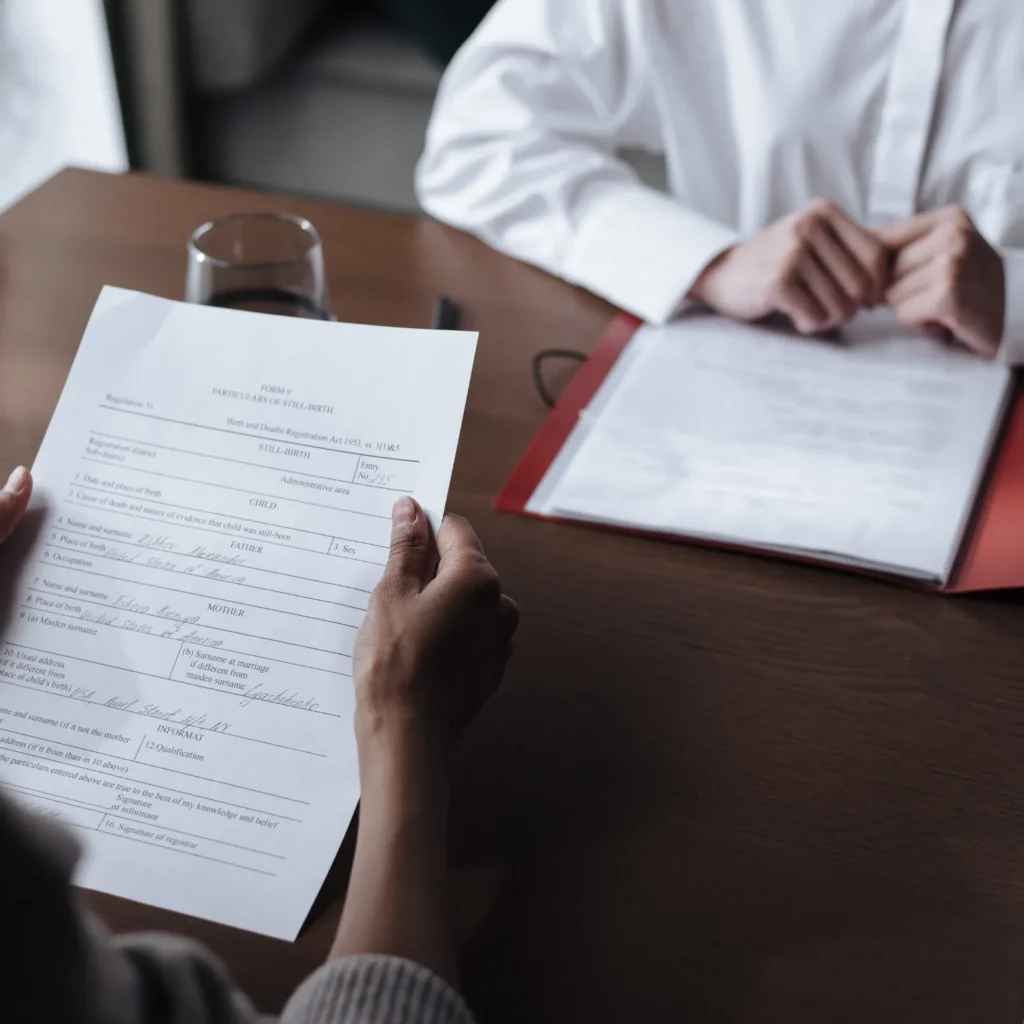 שני אנשים יושבים מול שולחן, אחד מחזיק מסמך ודן בו עם השני, דינמיקה של פגישת ייעוץ.